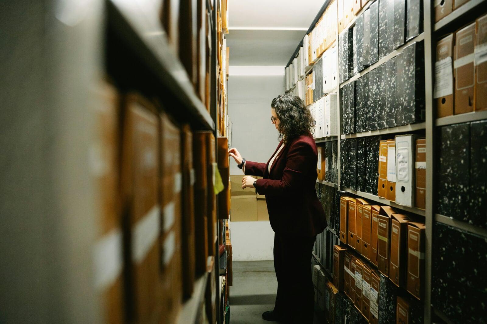 A woman pulling a file from a wall of binders