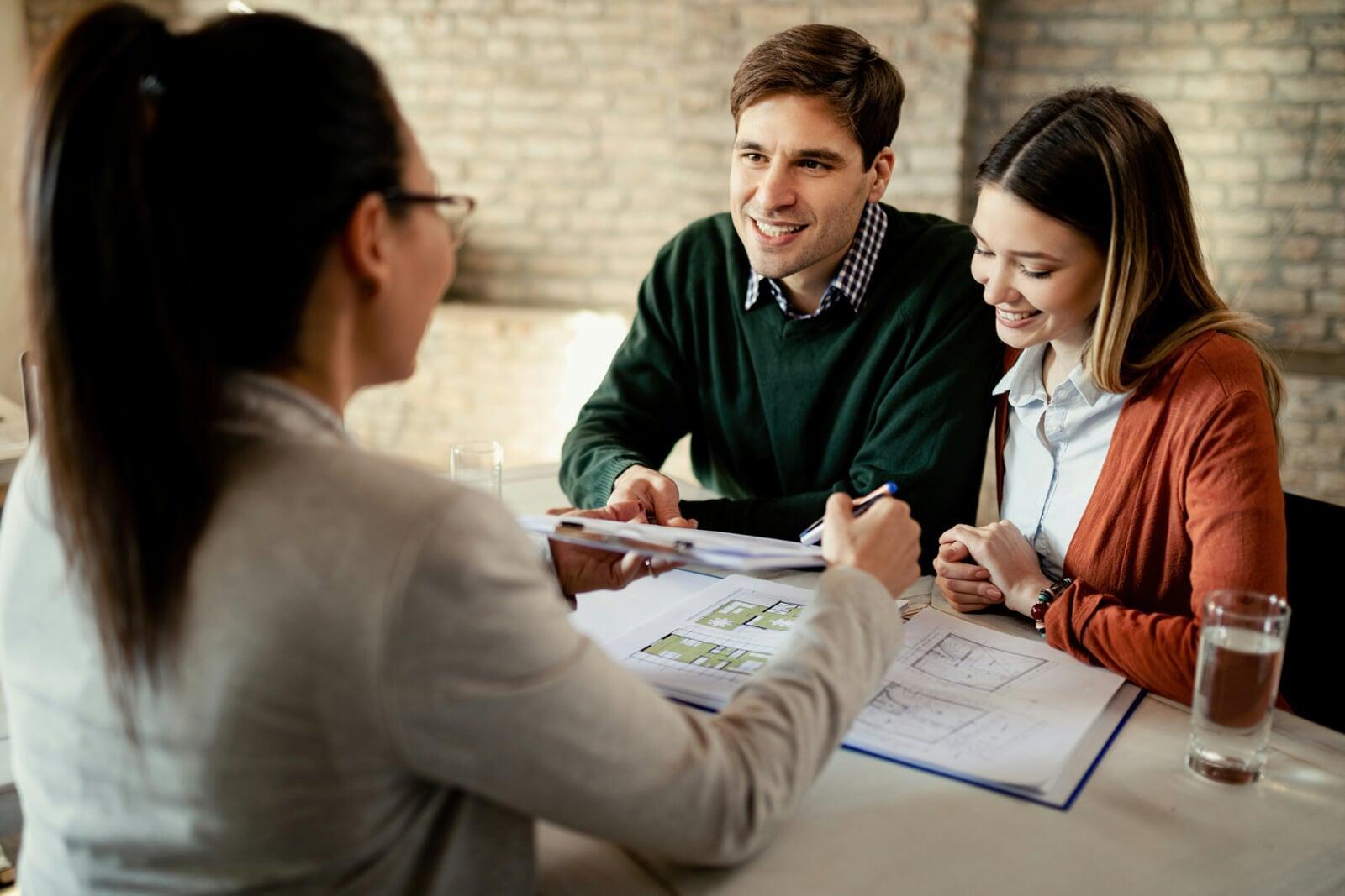 Three people meeting at a table, one signing a document